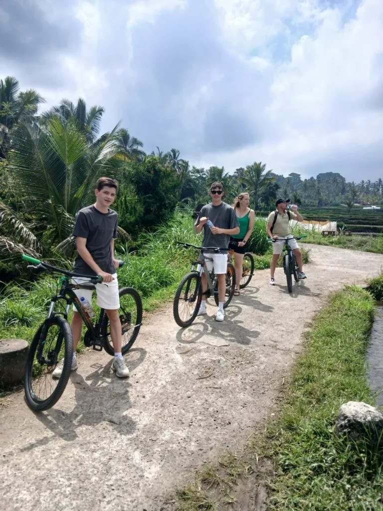 Cycling convoy pedaling through peaceful rural village lanes and family compounds with zero car traffic in Pejeng Bali