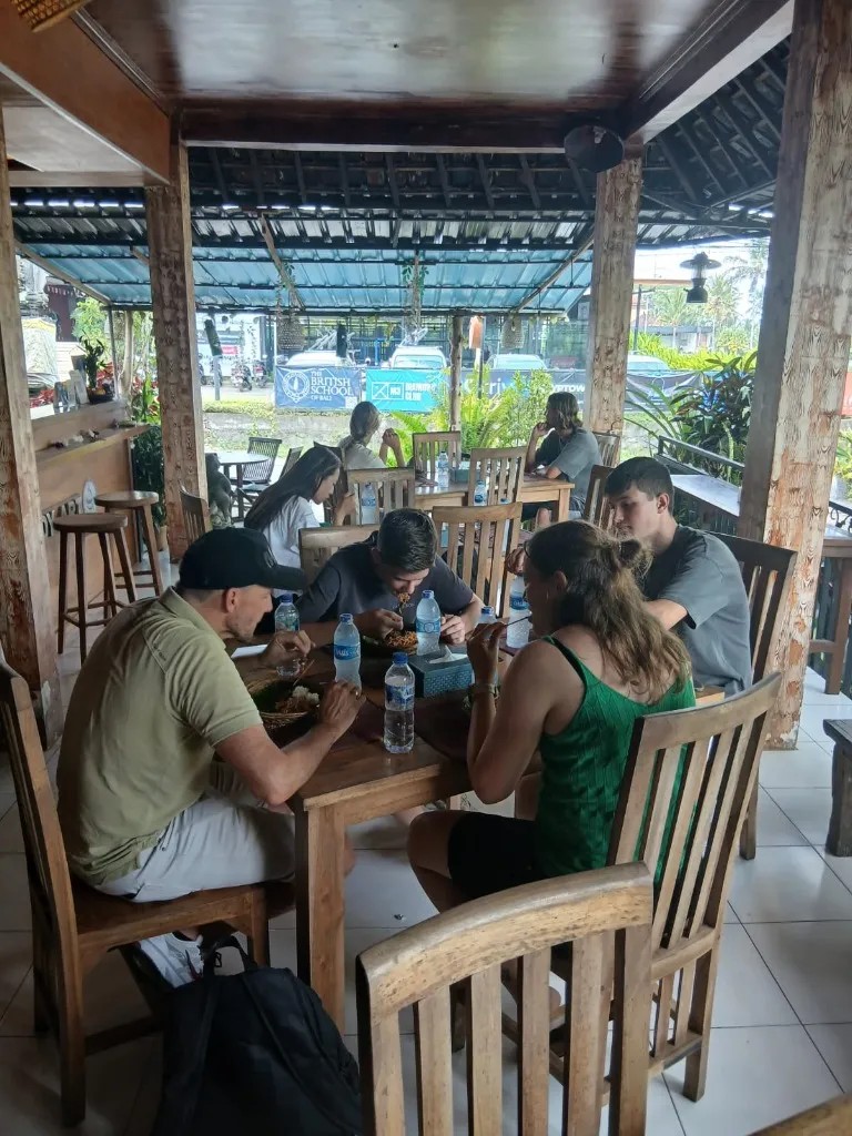 Traditional Balinese feast served at an open-air village pavilion overlooking emerald rice terraces after cycling